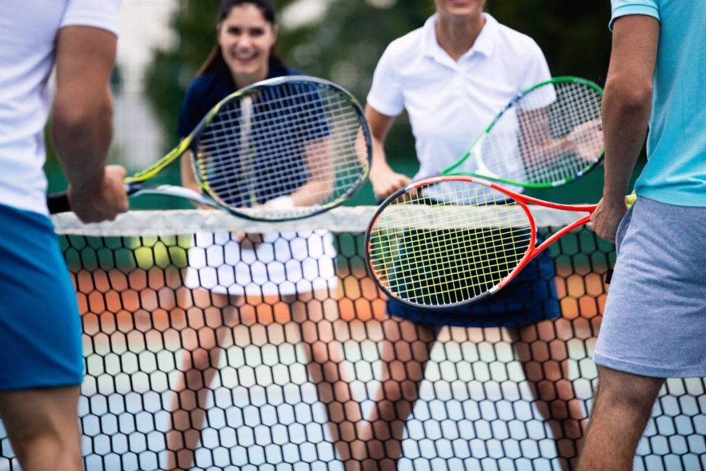 Happy fit people playing tennis together. Sport concept