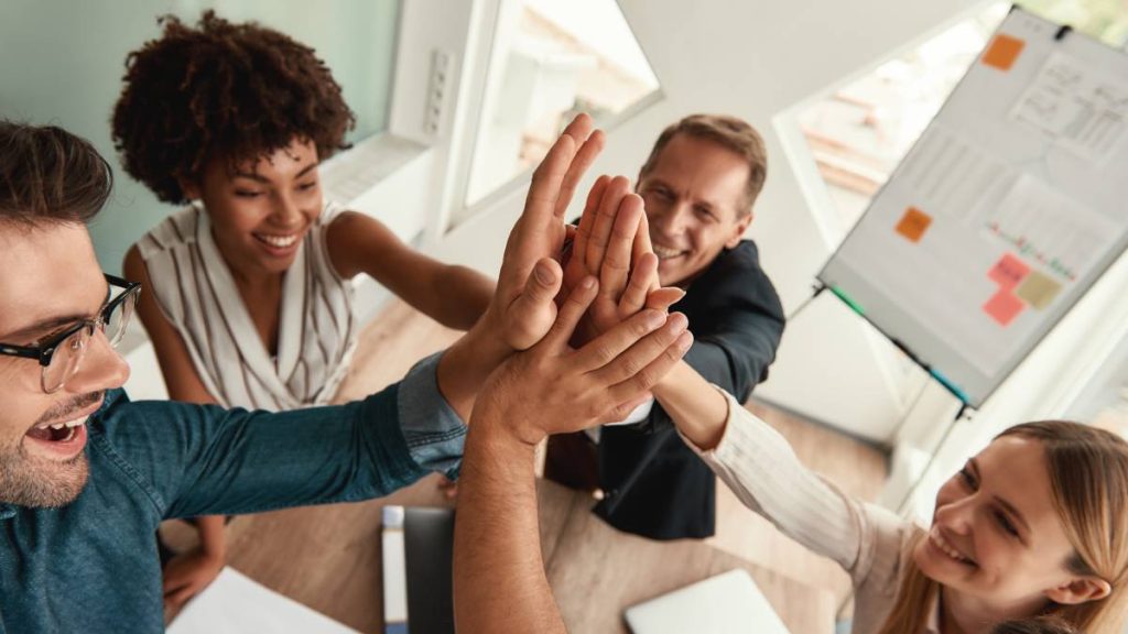 Well done Business people giving each other high-five and smiling while working together in the modern office. Teamwork. Success