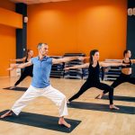 Yoga training class, female group with male trainer in action in gym. Yogi exercise indoor