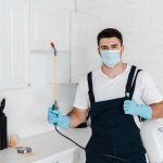 exterminator holding toxic spray near table with jars in kitchen