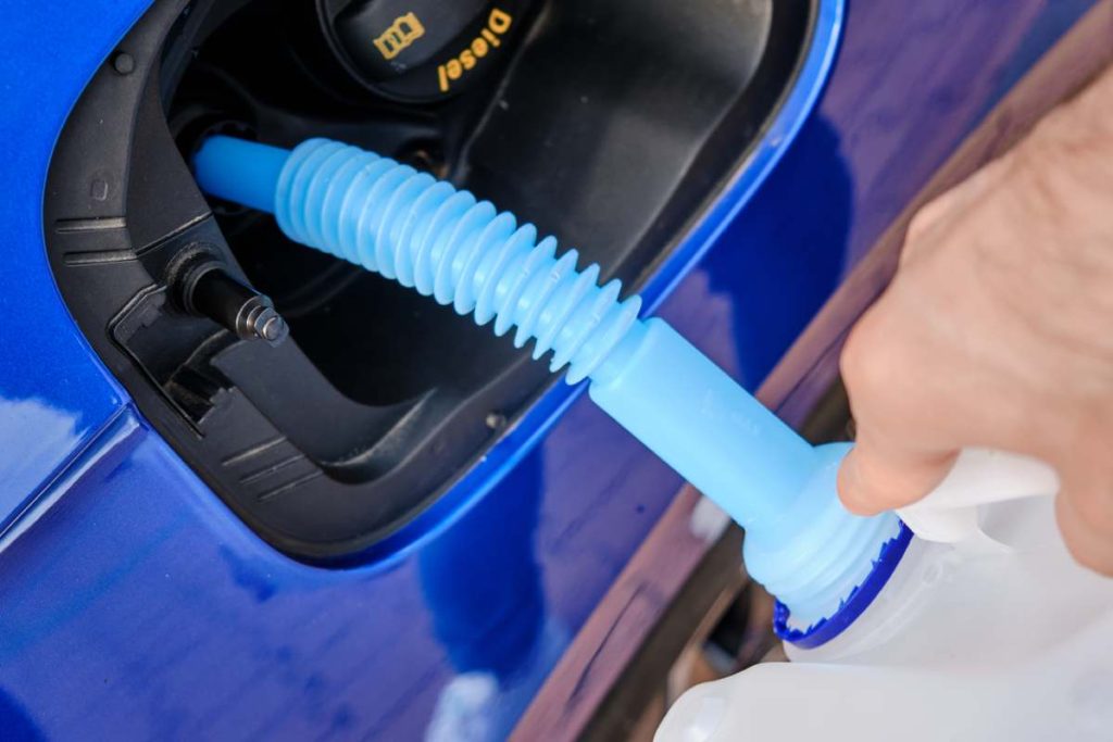 Close up filling of diesel exhaust fluid / AdBlue from canister into the tank of blue car for reduction of air pollution. Environmental or eco friendly solution.