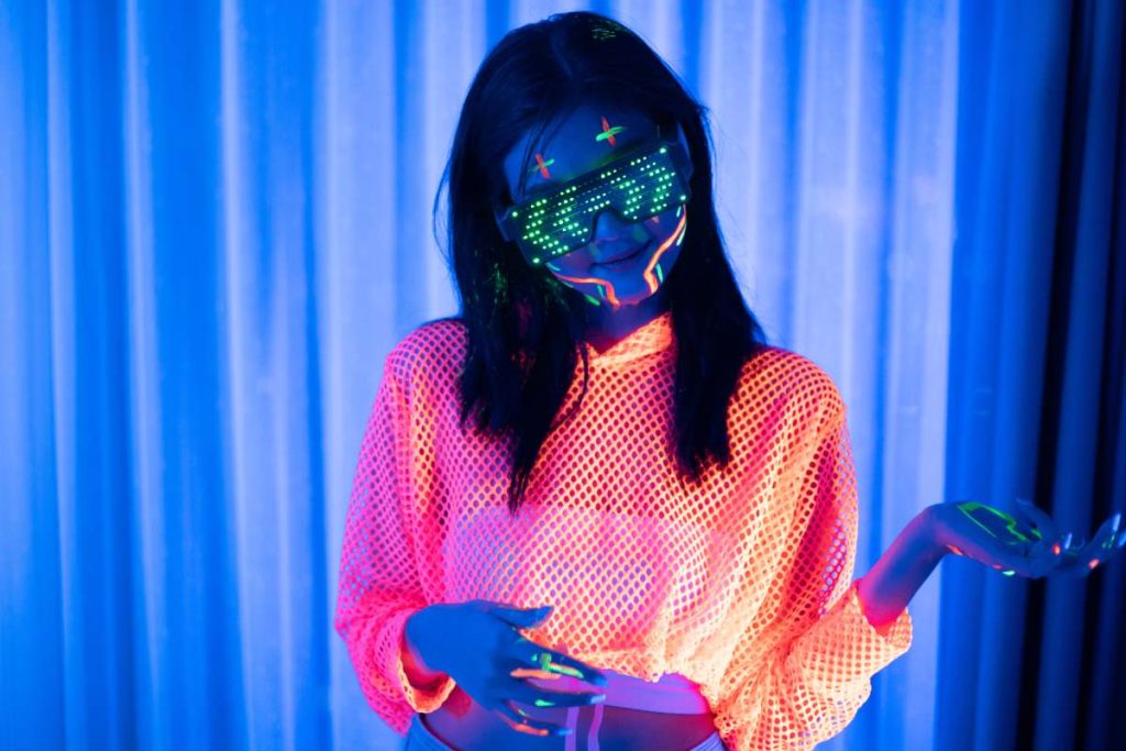 Neon  asian woman dancing. Fashion model woman in neon light, portrait of beautiful model with fluorescent make-up, Art and future design of female disco dancer posing in UV, colorful make up.