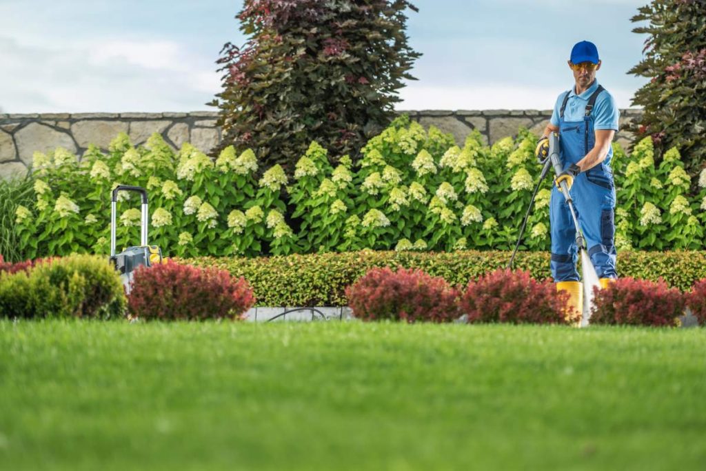 Caucasian Garden Keeper Cleaning Residential Driveway Using Professional Pressure Washer