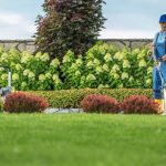 Caucasian Garden Keeper Cleaning Residential Driveway Using Professional Pressure Washer