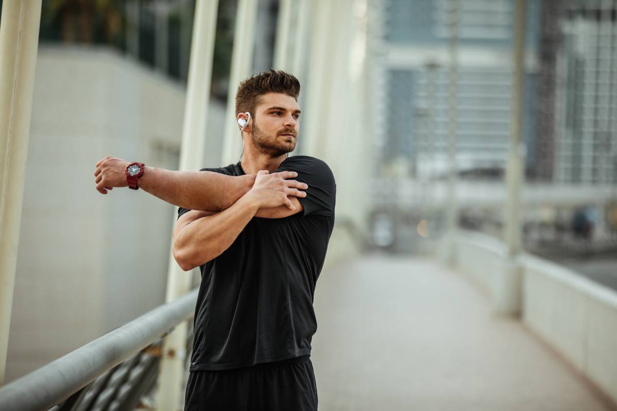 Young sportsman stretching before workout outdoors