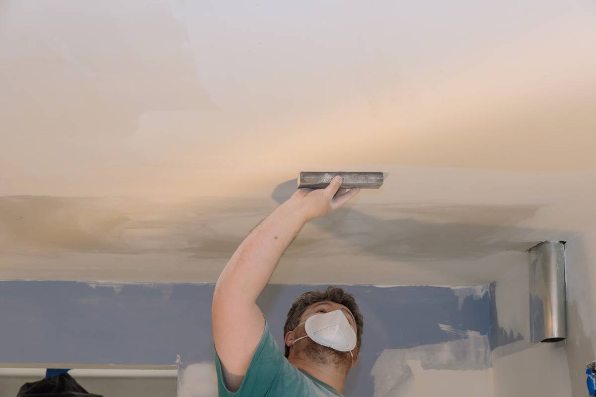 Sanding is being done by worker using sand trowel while renovating house in room where drywall mud being applied