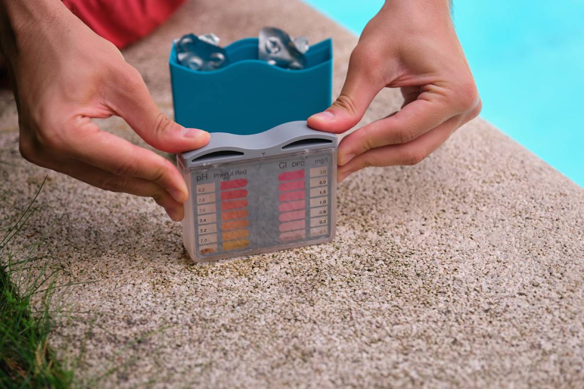 Unrecognizable young man using a ph and cl kit to test the swimming pool water quality.