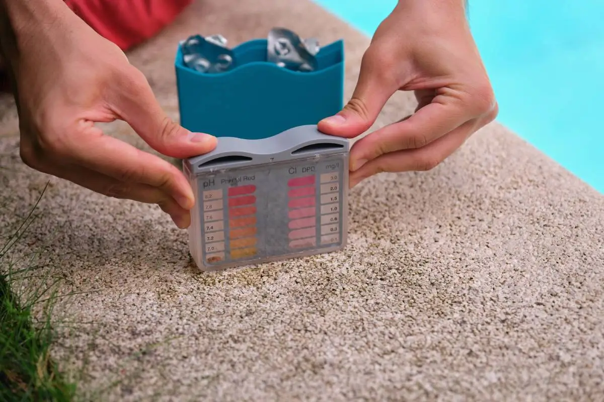 Unrecognizable young man using a ph and cl kit to test the swimming pool water quality.