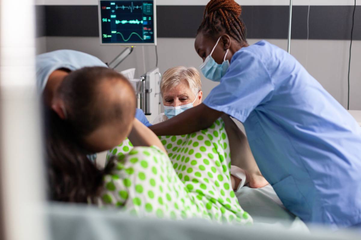 Woman delivery baby in hospital ward, screaming and pushing during caesarean surgery. Medical team and future father comforting pregnant woman with painful contractions in maternity clinic