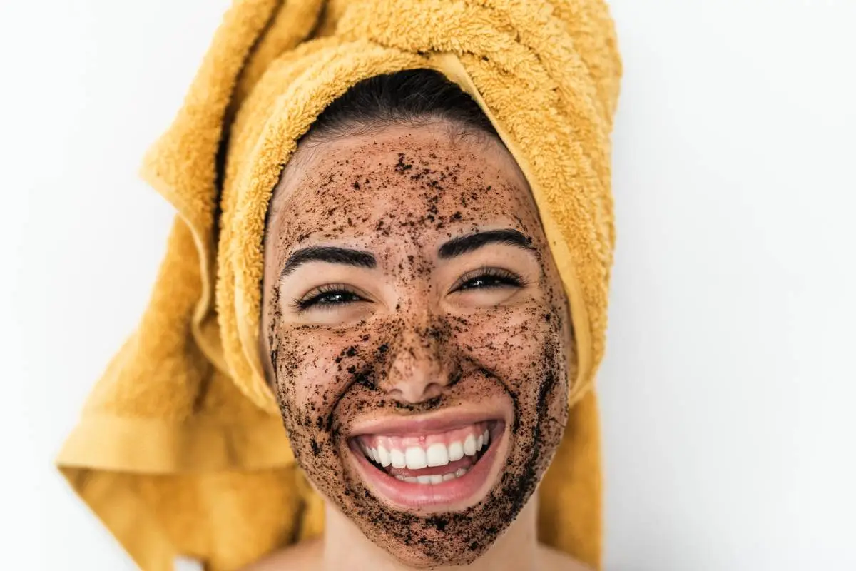 Young smiling woman applying coffee scrub mask on face - Happy girl having skin care spa day at home - Healthy alternative natural exfoliation treatment and youth people lifestyle concept